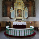 Kongen og Dronningen fikk høre Torild Haugann fortelle om kirken fra 1796 og altertavlen av den italienske kunstneren Joseph Pisani. Foto: Liv Anette Luane, Det kongelige hoff 